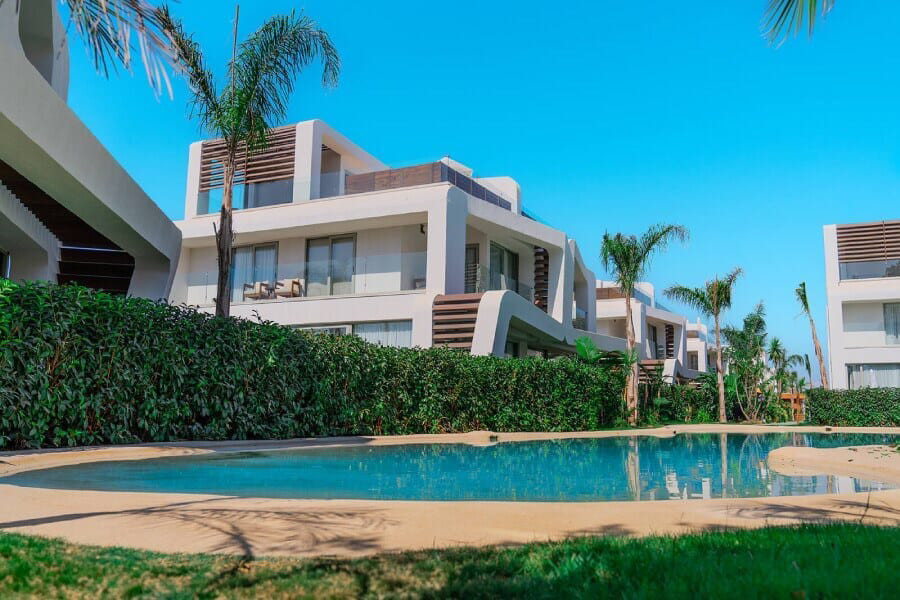 White villa buildings, hedge and a water edge in daylight