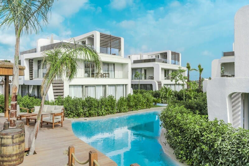 White villa buildings, palms and a long water edge in daylight